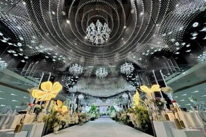 Un intérieur avec une allée centrale, des lustres et des compositions florales.