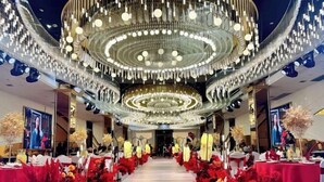 A grand hall with a central chandelier, red floral arrangements, and a polished floor. - Baili Hotel (Changshan)