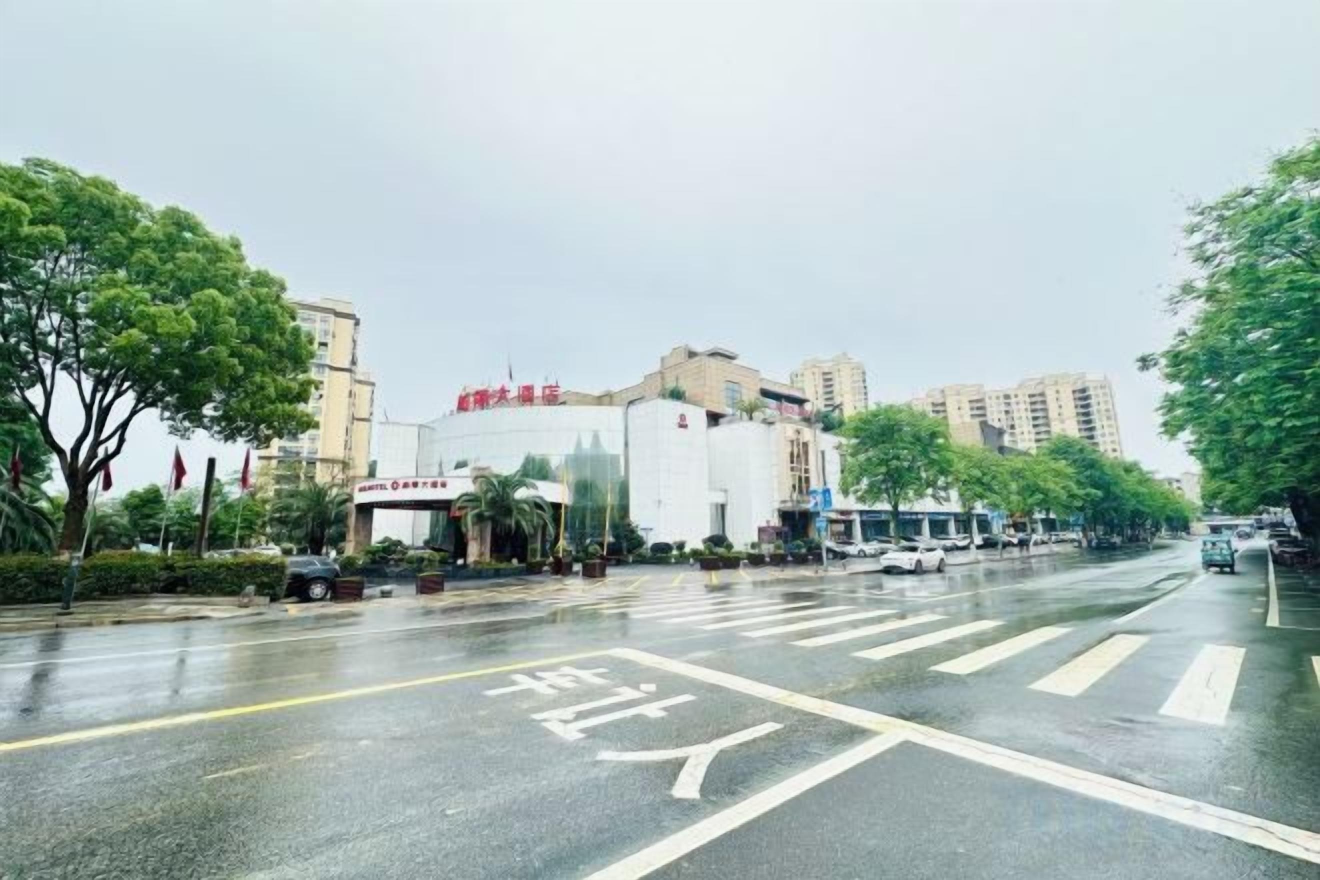 A street view with a building that has a sign with Chinese characters, a crosswalk, and vehicles on the road.