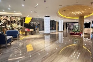 Un vestíbulo de hotel con piso pulido, zona de estar y detalles decorativos.