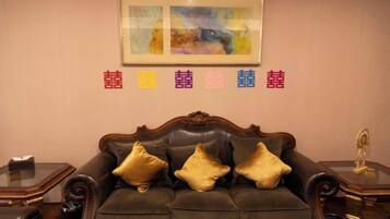 A room with a brown leather sofa, a framed artwork above it, and a decorative item on the right.