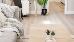 Un salon moderne avec un canapé, une table basse, un bureau et une plante en pot.