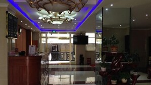 Eine Hotelhalle mit einer Rezeption, einem Chandelier und Topfpflanzen.