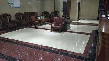 Un hall d’entrée avec un sol en marbre, des chaises en bois et un comptoir d’accueil.