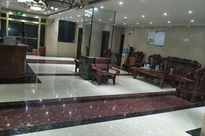 A hotel lobby with a reception desk, seating area, and a large mirror on the wall. - Shengchang Hotel (Xishuangbanna Gaozhuang Xishuangjing Branch) (Jinghong)