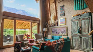 A cozy living room with a large window, a sofa, chairs, and a cabinet. - Mayupata in Calca by Wynwood House (Calca)