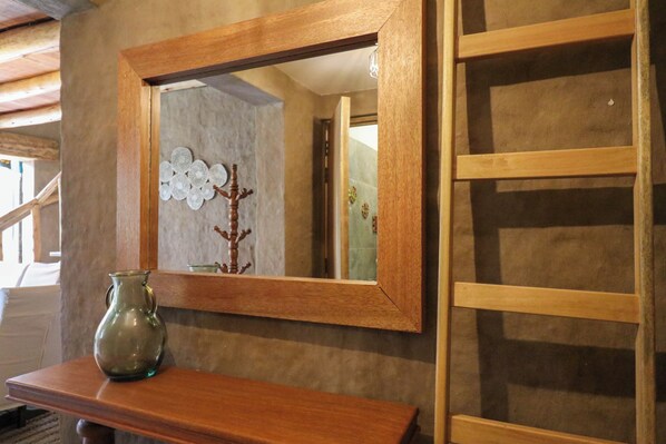 A wooden mirror with a simple frame on a wall, a wooden shelf below it, and a wooden ladder to the right. - Mayupata in Calca by Wynwood House (Calca)