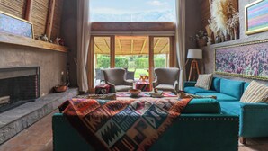 A living room with a fireplace, a sofa, and a view of the outdoors. - Mayupata in Calca by Wynwood House (Calca)