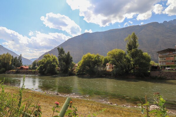 A river with houses on the banks, surrounded by mountains and trees. - Mayupata in Calca by Wynwood House (Calca)