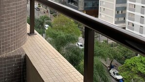 Balcón con baranda metálica que da a una vista urbana con edificios altos y una calle con vehículos.