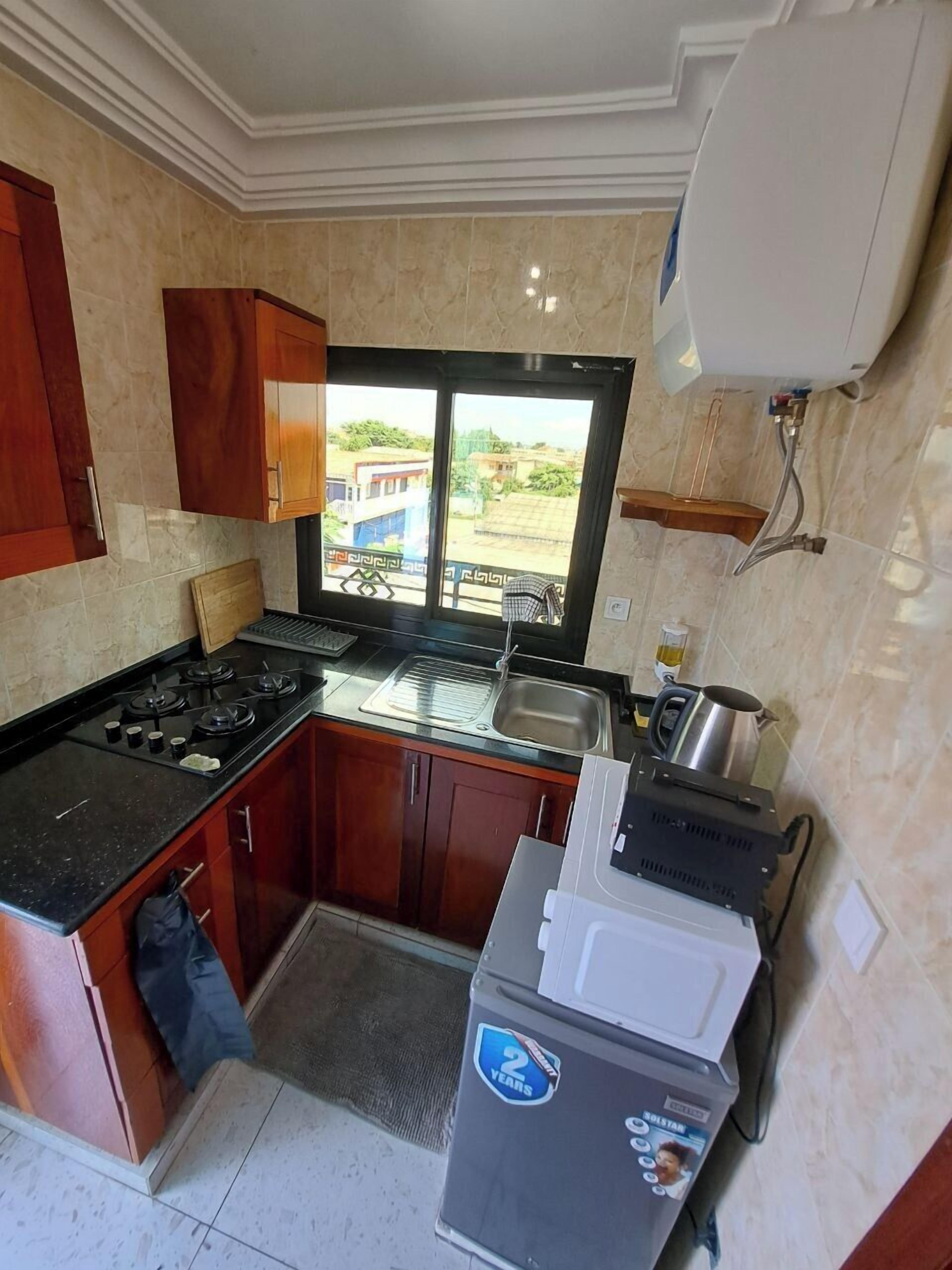 A kitchen with a gas stove, sink, and a window with a view of buildings.
