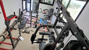 Una palestra con diverse attrezzature per l'allenamento, una panca e una finestra che lascia entrare luce naturale.