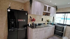 Una cucina moderna con un frigorifero nero, mobili chiari e un tappeto grigio.