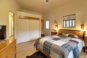 Une chambre à coucher avec un lit, une commode, un téléviseur, une fenêtre et une porte.
