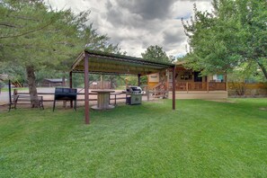 Un espace extérieur aménagé en terrasse, avec un coin salon couvert, un barbecue et une table de pique-nique.