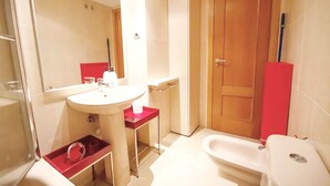 A bathroom with a sink, mirror, toilet, and a red cabinet.