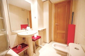 A bathroom with a sink, mirror, toilet, and a red cabinet. - campezo (Madrid)