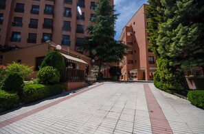 A courtyard with a paved walkway, surrounded by buildings with balconies and a small structure with a roof. - campezo (Madrid)