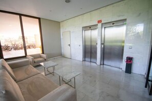 A modern lobby with a sofa, a small table, and an elevator. - campezo (Madrid)