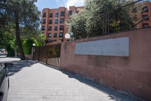 A paved walkway with a metal fence and a wall with a plaque. - campezo (Madrid)