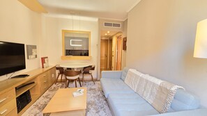 A modern living room with a flat-screen TV, a dining table with chairs, and a light blue sofa. - campezo (Madrid)