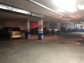 A multi-level parking garage with concrete pillars and yellow parking lines. - campezo (Madrid)