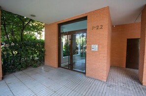 A building entrance with a glass door, a brick wall, and a tiled floor.