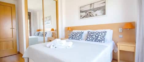 A hotel room with a large bed, a wardrobe, a bedside table with a lamp, and a painting on the wall.