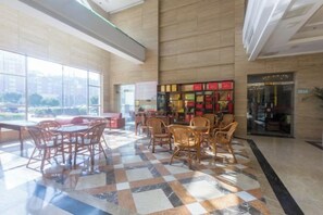 A spacious lobby with a checkered floor, wooden furniture, and a large window offering a view outside. - Junhao Hotel (Xiushui)