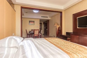 A hotel room with a bed, a desk, a chair, a television, and a lamp. - Junhao Hotel (Xiushui)