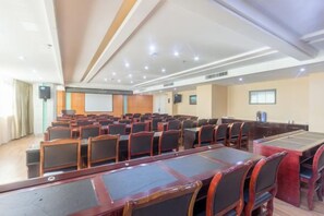 A conference room with rows of chairs and a long table, equipped with a projector screen and speakers. - Junhao Hotel (Xiushui)