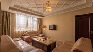 Una camera d'albergo con una grande finestra, una televisione a schermo piatto, un tavolino in legno e due divani in pelle.