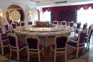 Une table de salle à manger ronde, avec des chaises, un lustre et un élément décoratif central.