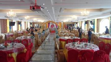 A banquet hall with round tables, red tablecloths, and a central aisle.
