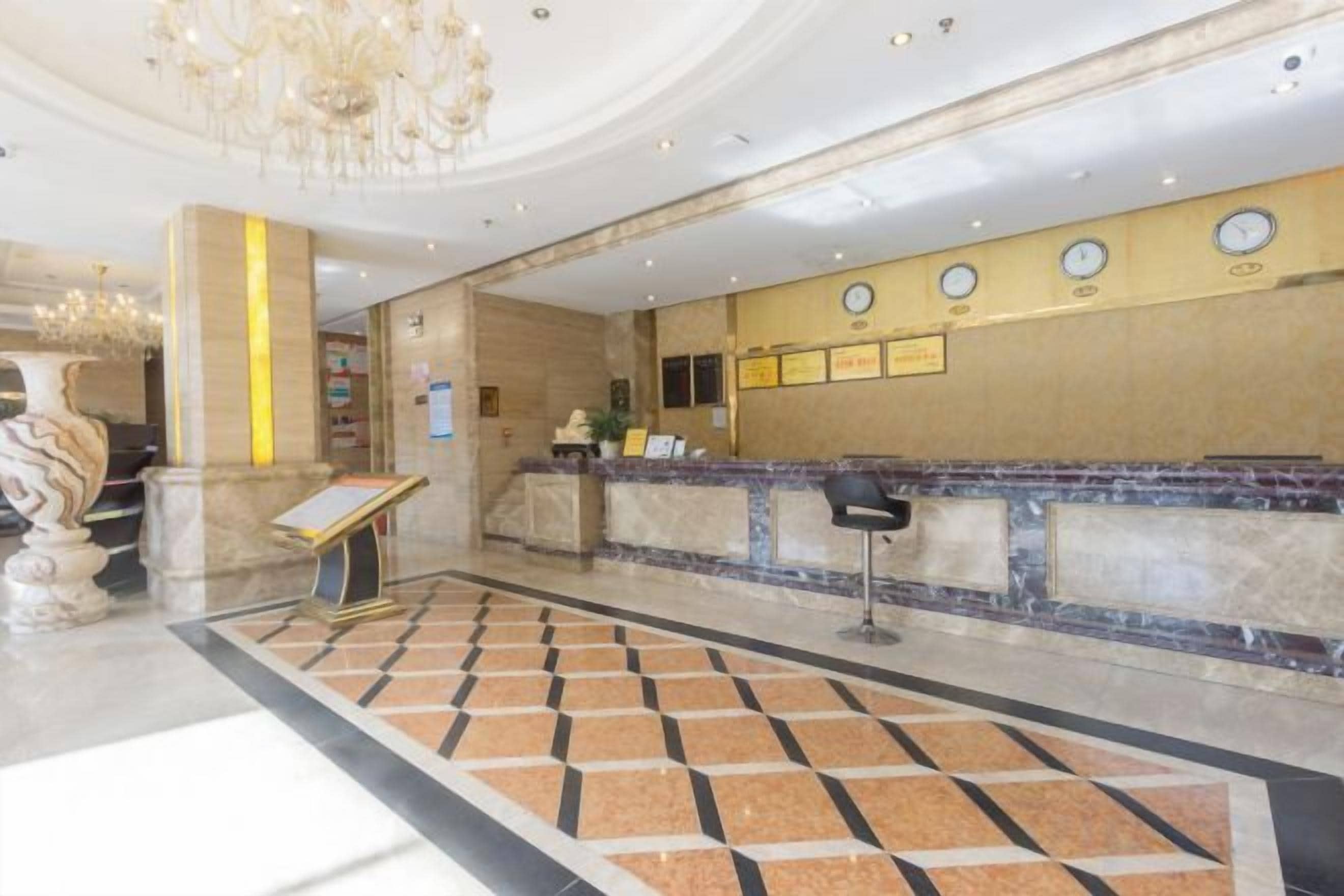 Een hotellobby met een receptiebalie, een kroonluchter en een versierde vloer.