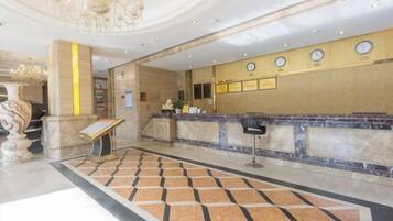 Een hotellobby met een receptiebalie, een kroonluchter en een versierde vloer.