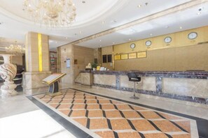 A hotel lobby with a reception desk, a chandelier, and a patterned floor. - Junhao Hotel (Xiushui)