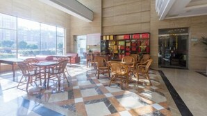 Un'ampia hall con pavimento a scacchi, sedie in legno e una libreria.