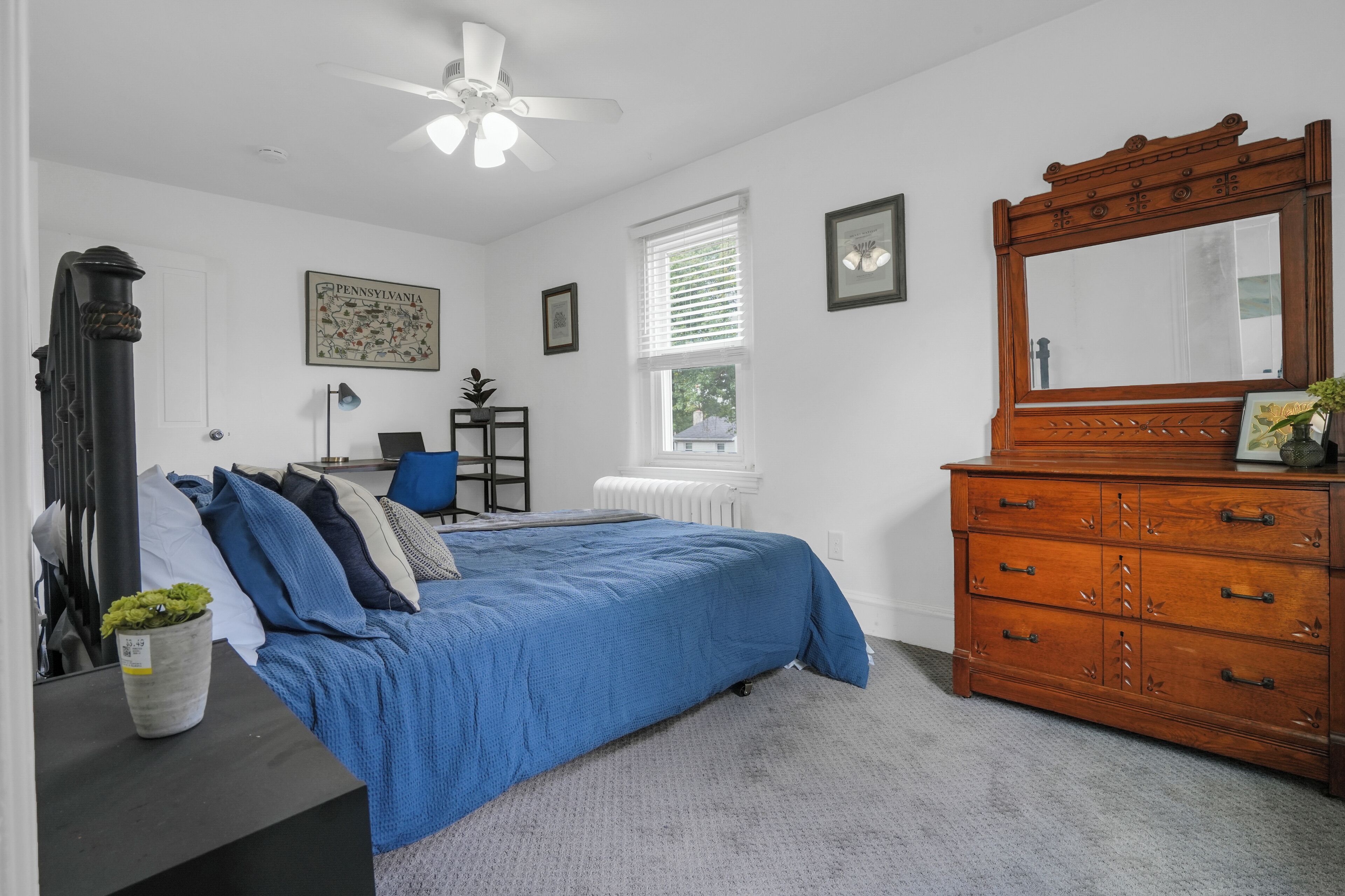 A bedroom with a bed, dresser, and a ceiling fan.
