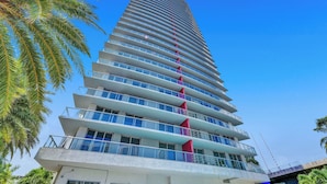 A tall, modern hotel with multiple balconies and a clear sky. - Beachwalk Condo (Hallandale Beach)