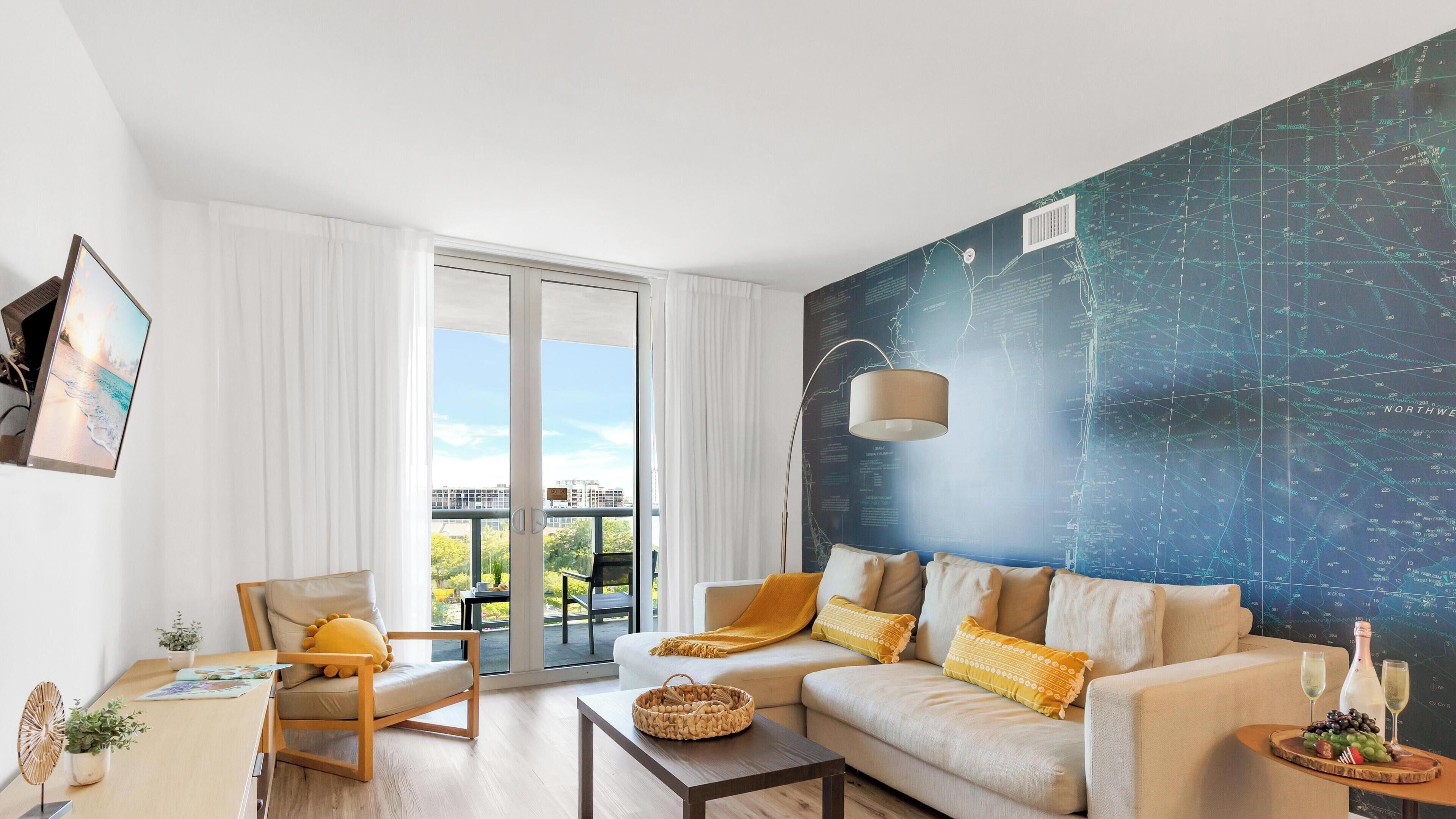 A modern living room with a large window, a sofa, a chair, and a wall-mounted map.