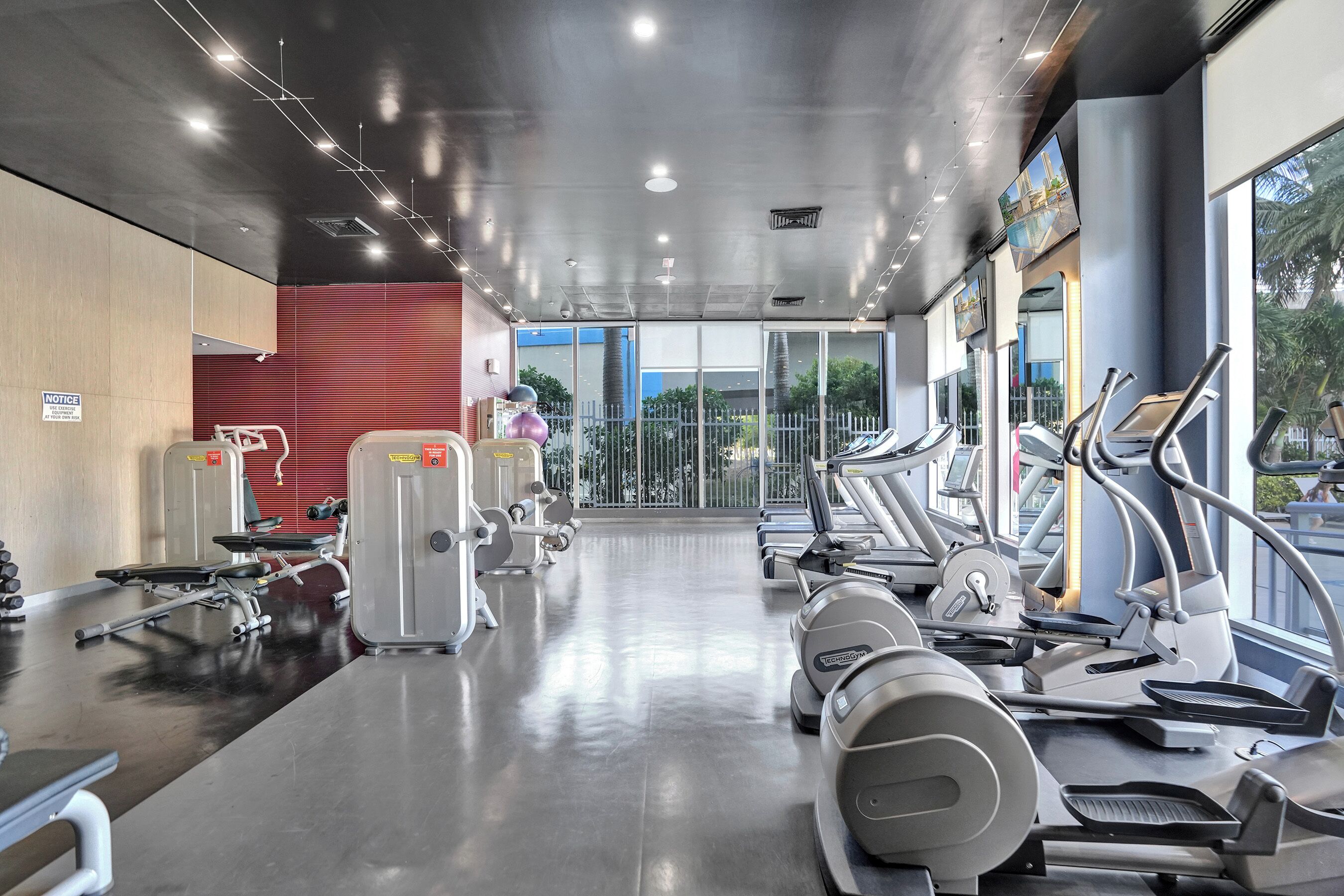 Une salle de sport équipée de tapis de course, d’appareils de musculation et d’un mur recouvert de miroirs.