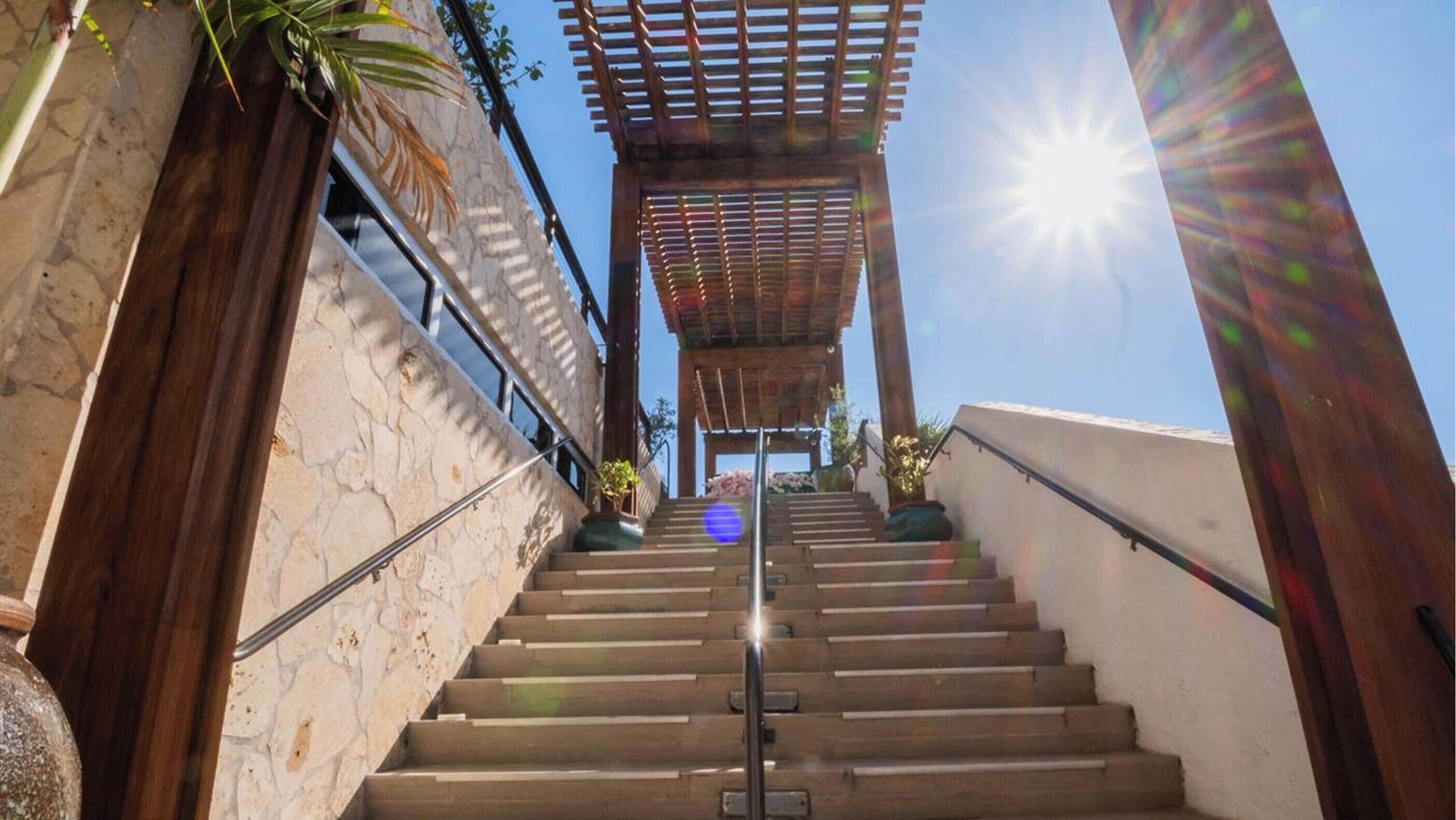 A staircase leading up to a wooden pergola with a clear sky above.