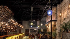 A bar area with a brick wall, wooden shelves, and hanging lights. There are tables and chairs arranged for seating. - 6 En-Suite Bedrooms · Rooftop Pool · Restaurant Below | Tulum (Tulum)