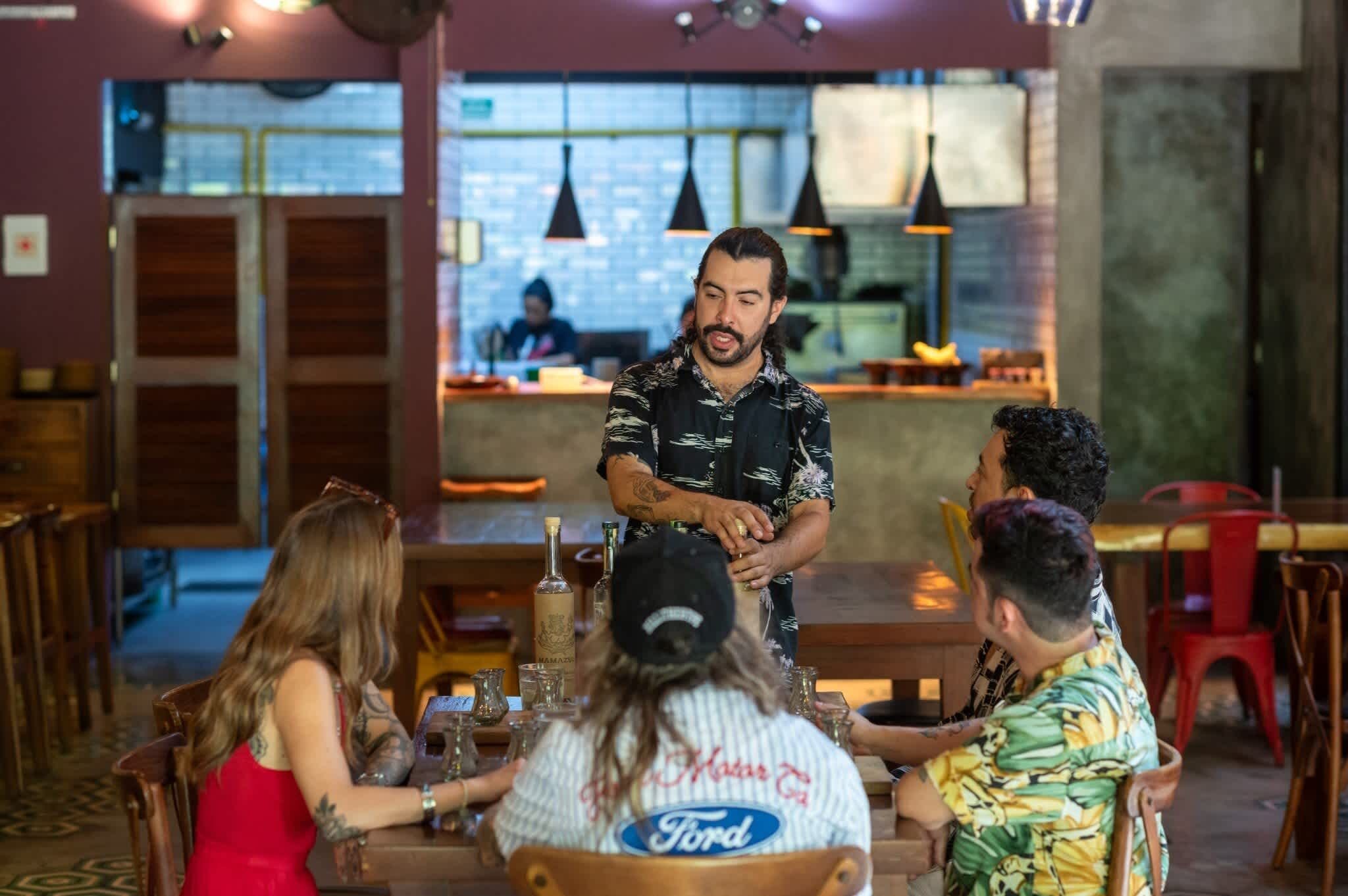 Een restaurantinterieur met houten tafels, stoelen en hangende pendantlampen.