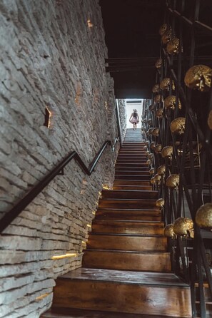Un escalier avec des murs en pierre et des marches en bois menant à un niveau supérieur.