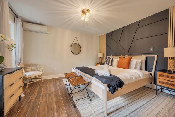 Un dormitorio moderno con cama, mesitas de noche, una silla y un aparador.