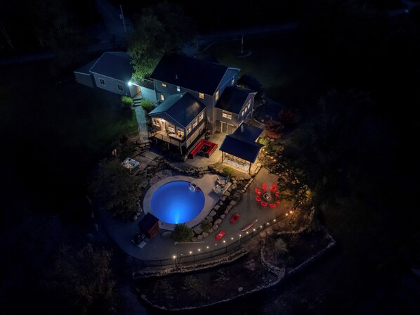 Una casa grande con piscina, zona de estar exterior y un patio cubierto.