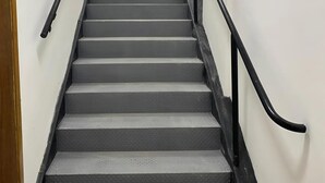 A staircase with a handrail and a wooden door frame.