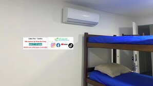 A bunk bed room with a white air conditioner above it. There is a sign on the wall with text and logos.